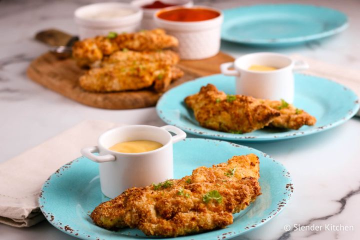 Air fryer chicken tenders with honey mustard sauce on two blue plates. 