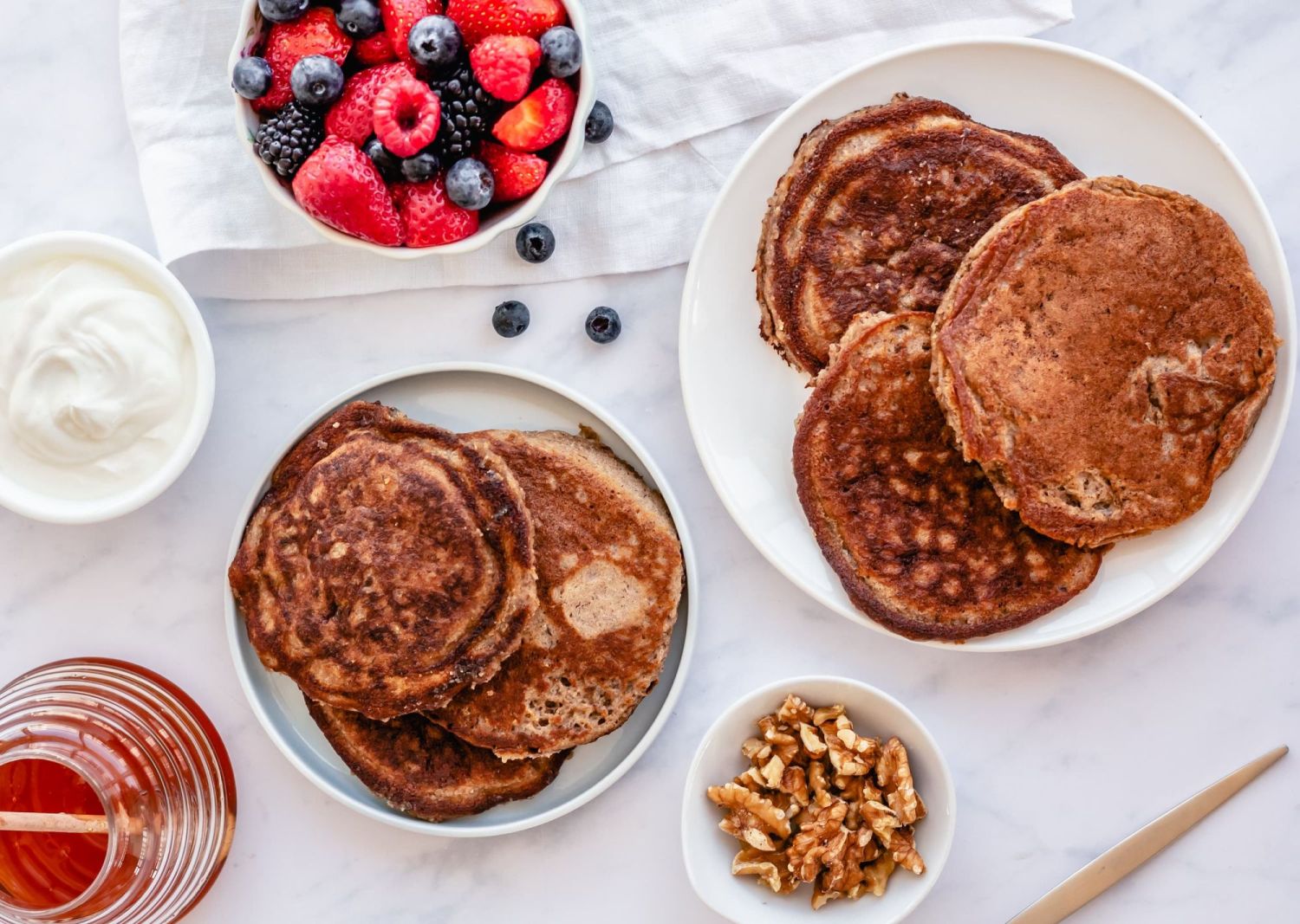 Low carb almond flour pancakes with flaxseed meal on a plate with fresh berries, yogurt, and honey.