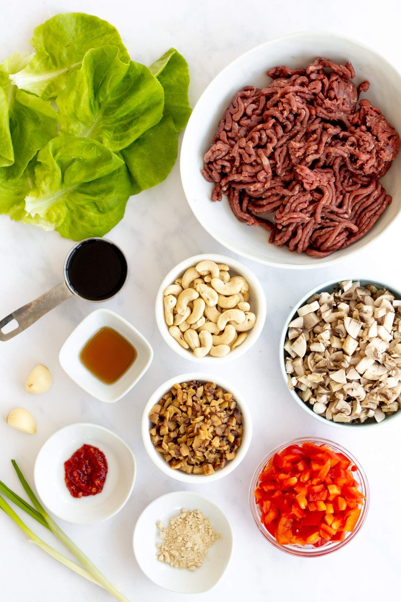 Ingredients for Asian beef lettuce wraps including ground beef, peppers, mushrooms, water chestnuts, and soy sauce.