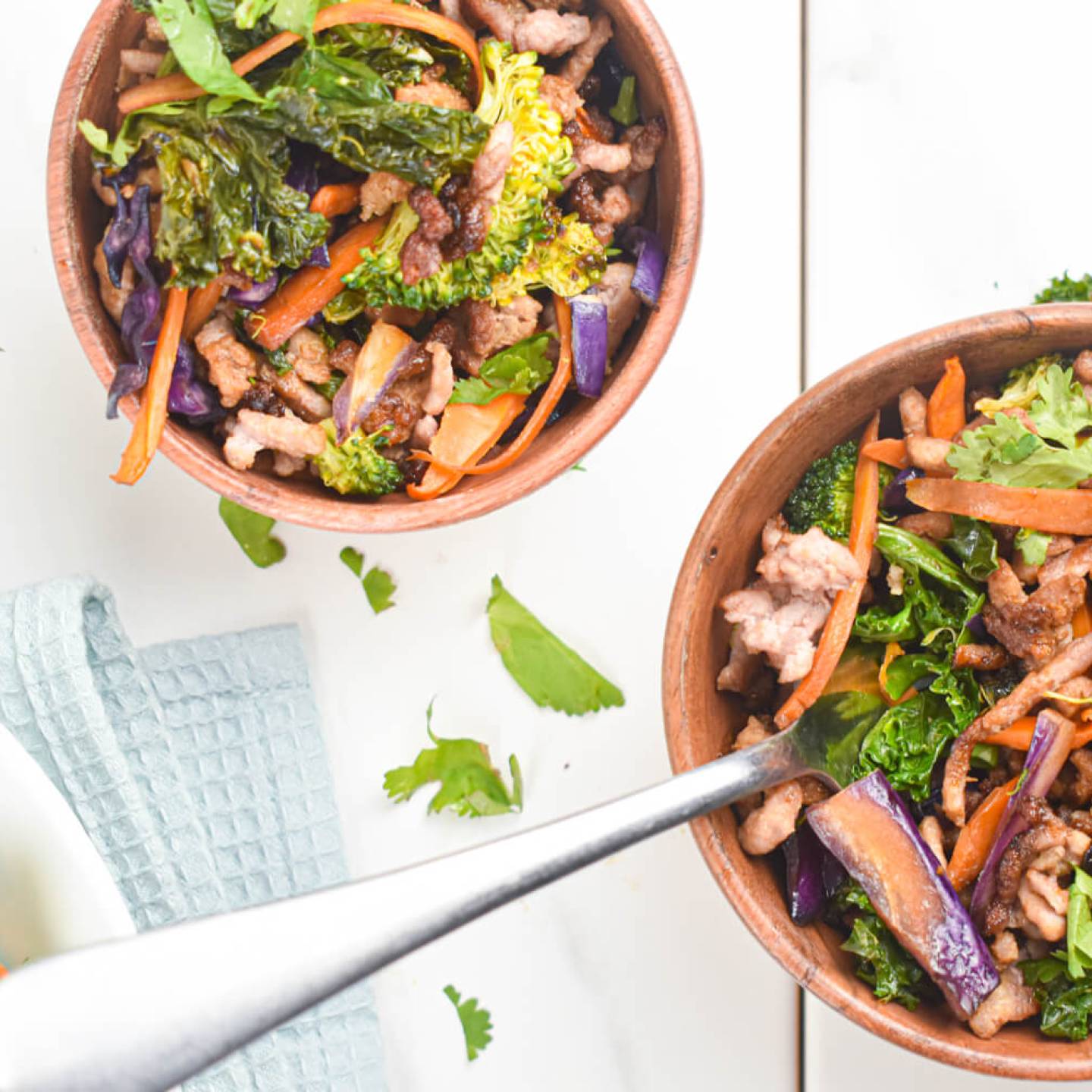 Asian ground turkey stir fry with kale, carrots, broccoli, and soy sauce in two bowls.