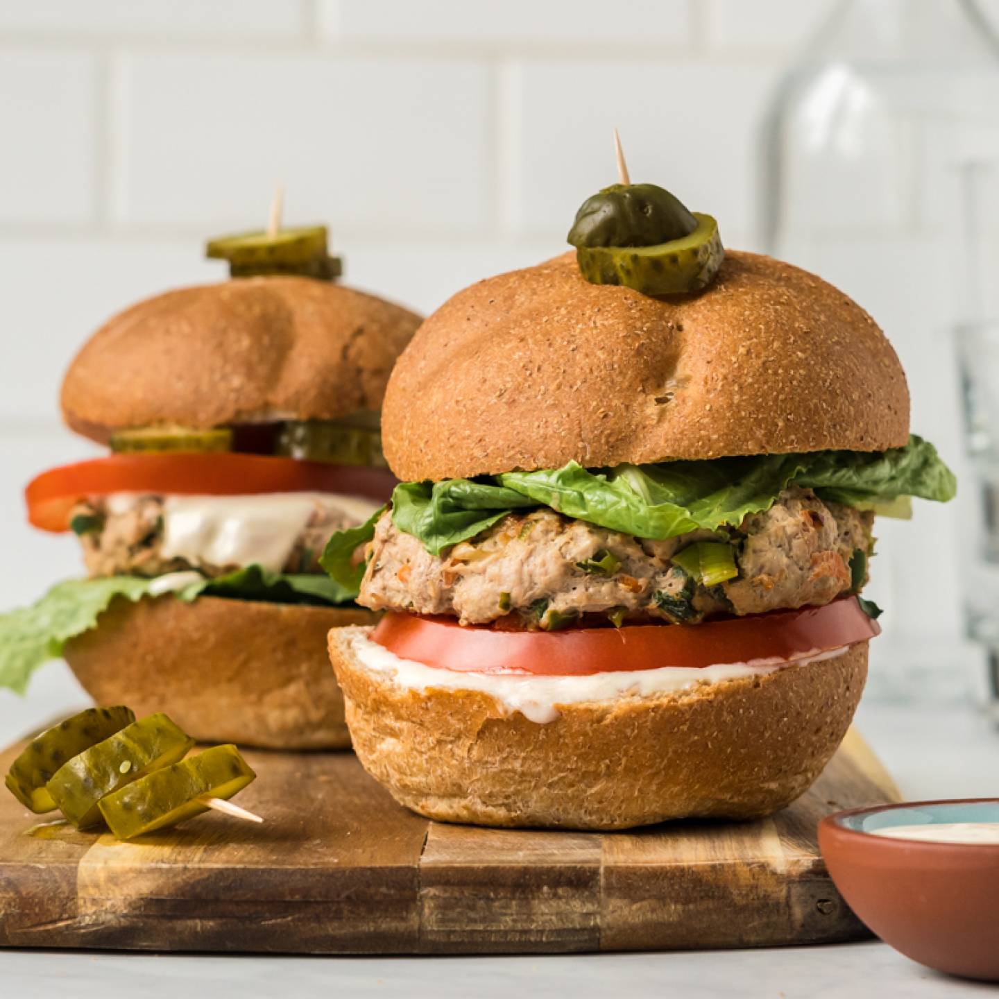 Asian turkey burgers with lettuce, tomato, and sweet chili yogurt sauce on two buns,