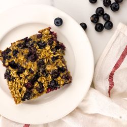 Baked blueberry oatmeal with rolled oats and blueberries on a plate.