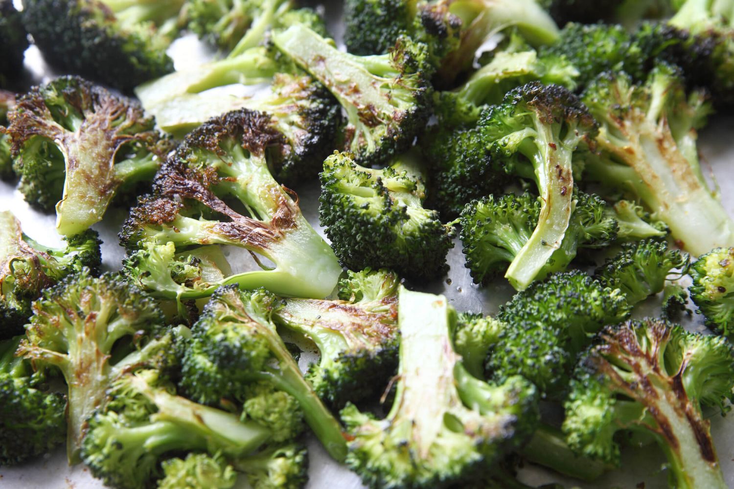 Roasted broccoli on a sheet pan with burnt crispy edges.