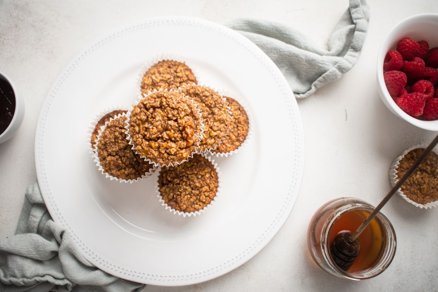 Oat muffins made with rolled oats, bananas, and flaxseed baked in muffin cups with maple syrup and fruit on the side.