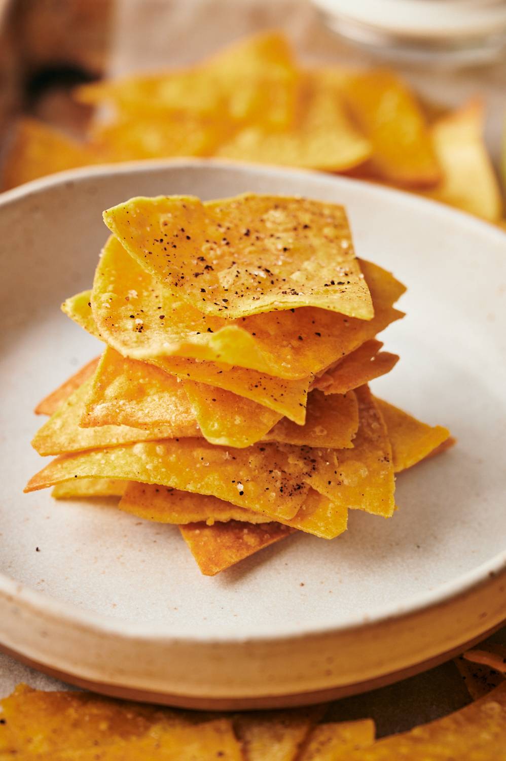 Homemade baked tortilla chips stacked on a plate.