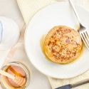 Banana flax pancakes on a plate with syrup on the side.