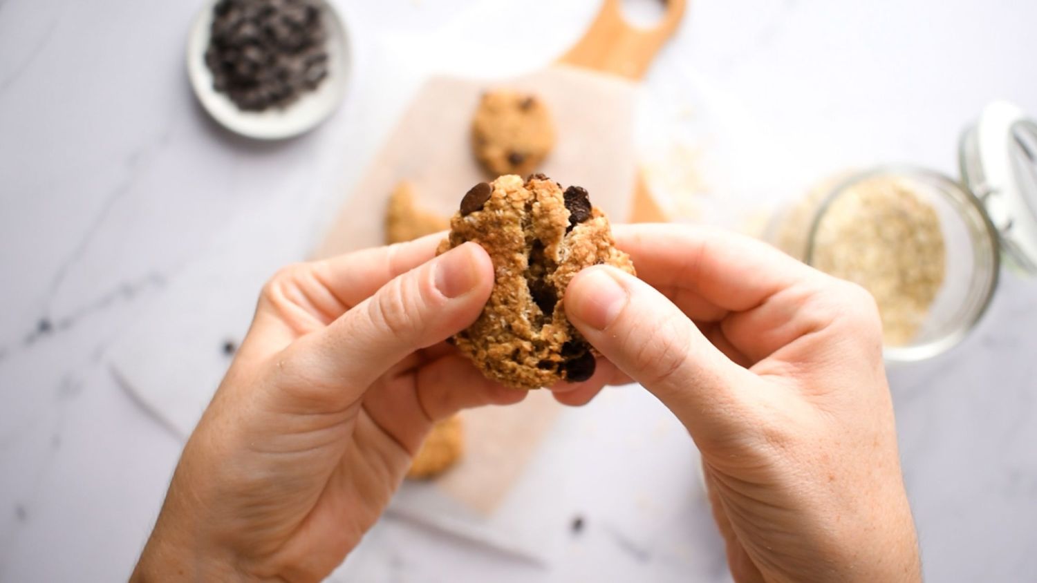 Cookie made with oatmeal, bananas, peanut butter, and chocolate chips in a hand.