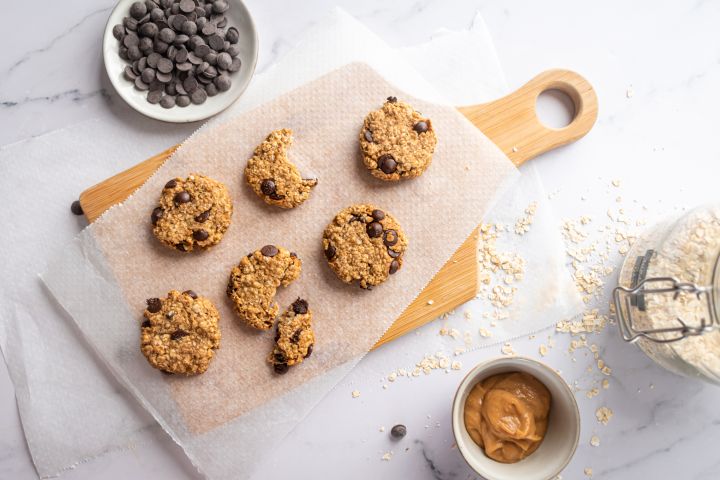 Banana oatmeal cookies with chocolate chips on a wooden cutting board.