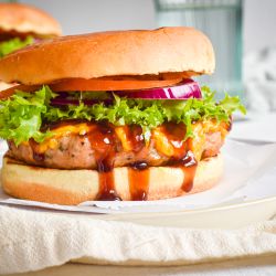 Barbecue cheddar turkey burgers made with lean ground turkey on a roll with lettuce. red onion, and tomato.