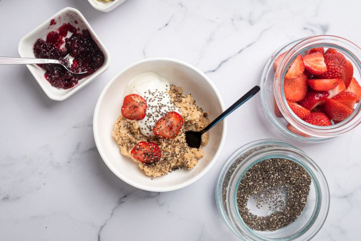 Microwave oatmeal with fresh fruit in a bowl with a spoon and Greek yogurt.