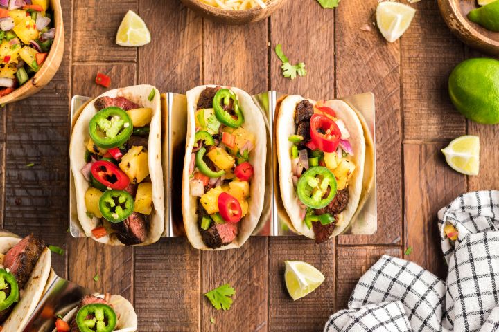 Blackened steak tacos with seared steak served on flour tortillas with pineapple salsa, cilantro, and jalapenos.