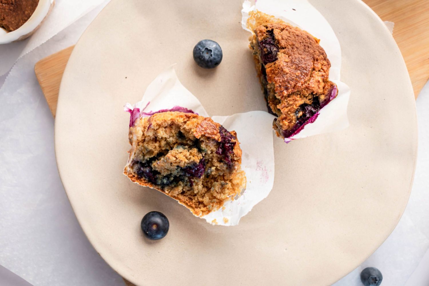 Golden brown blueberry oatmeal muffin cut in half and served on a plate with fresh berries.