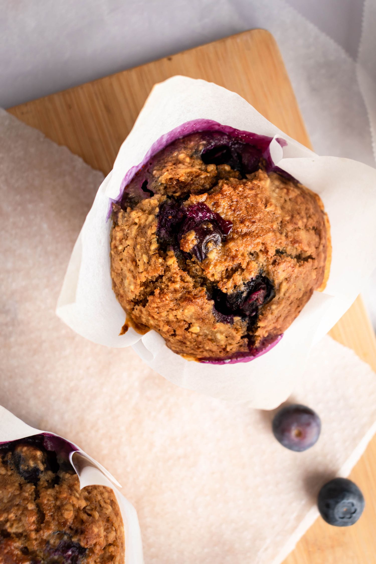 Baked oatmeal and blueberry muffins with a golden brown top served in parchment paper.