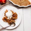 Breakfast apple crisp served on a plate with tender baked apples, an oat crumble, and yogurt.