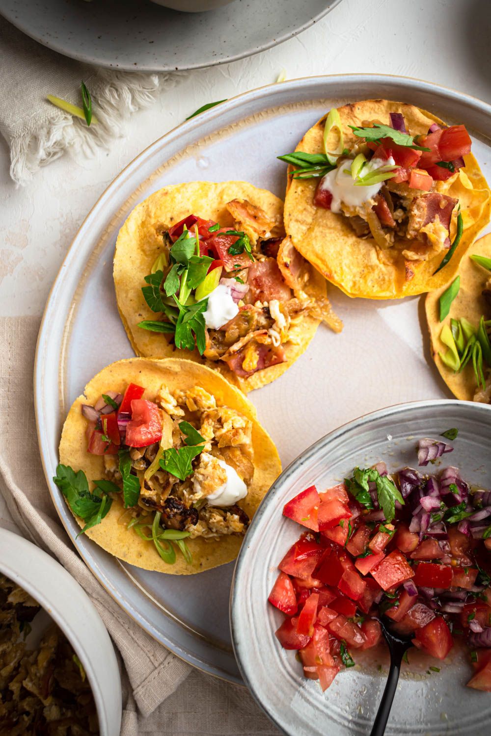 Turkey bacon breakfast tacos with scrambled eggs and potatoes served in corn tortillas with sour cream, salsa, and cilantro.