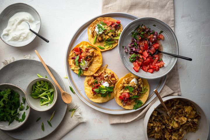 Breakfast tacos with eggs, bacon, and potatoes served in corn tortillas with salsa, sour cream, cilantro, and green onions.