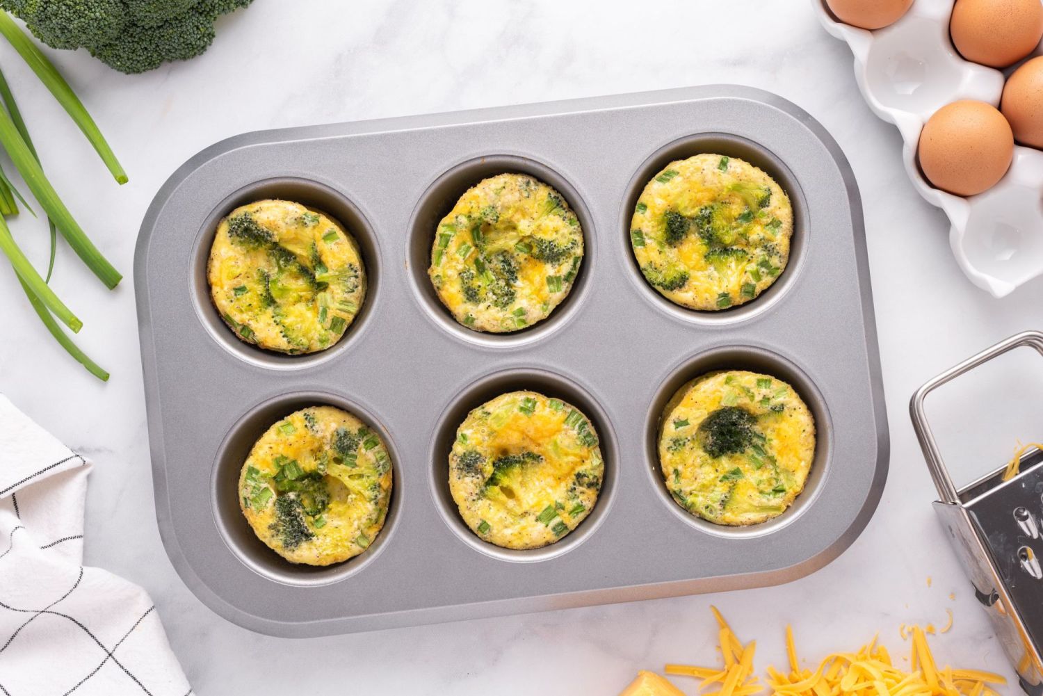 Muffin tin filled with baked broccoli cheese egg muffins.