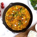 Broccoli and cheese frittata cooked in a skillet with eggs, broccoli, ricotta cheese, and tomatoes.