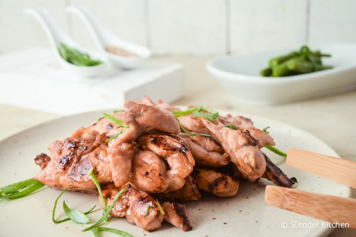 Broiled Asian Chicken Thighs with chopsticks, green onions, and sesame seeds.