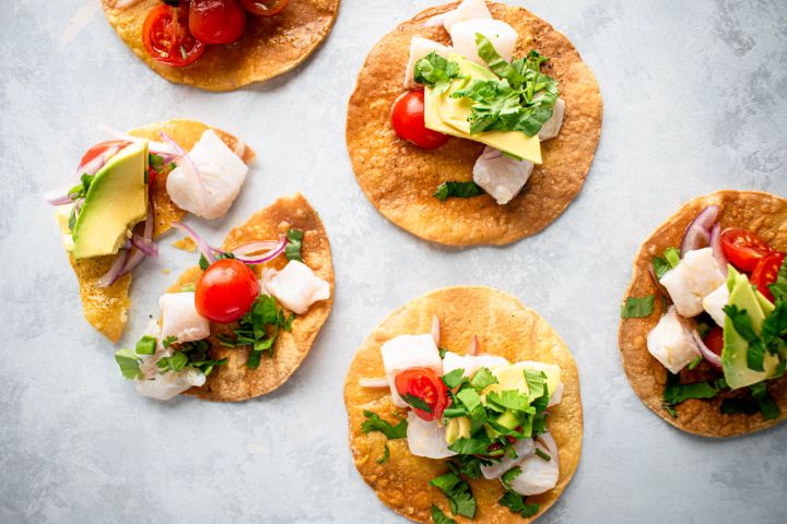 Ceviche tostadas with fish ceviche on a baked tostada shell topped with avocado and cilantro.