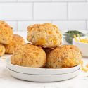 Cheddar biscuits baked until golden brown piled on a plate.