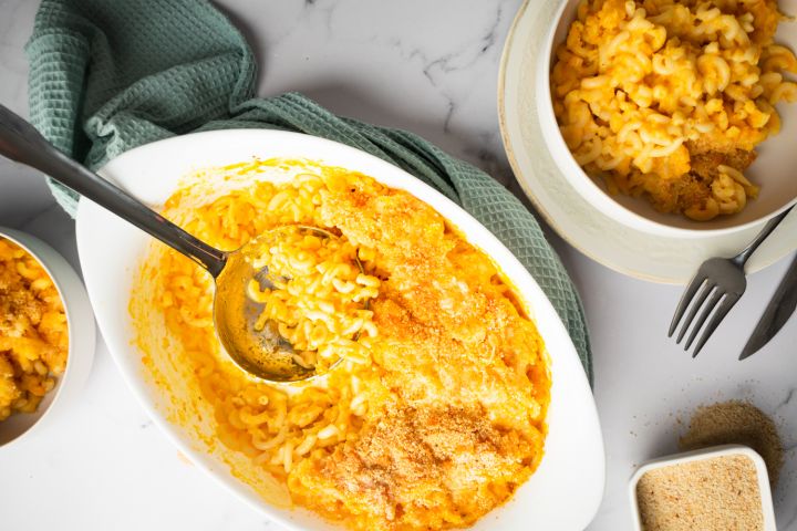 Cheddar carrot macaroni and cheese in a baking dish with crispy breadcrumbs on top.