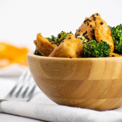 Chicken broccoli stir fry with stir fry sauce in a wooden bowl with sesame seeds.