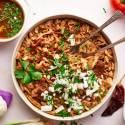 Chicken birria served in a bowl with shredded chicken in a red chile sauce with cilantro and onions.