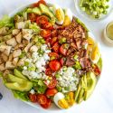 Chicken cobb salad with lettuce, grilled chicken, boiled eggs, bacon, tomatoes, and blue cheese.