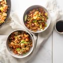 Chicken pineapple fried rice served in two bowls with fresh pineapple, chicken breast, brown rice, and vegetables with cashews.