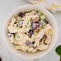 Chicken salad with grapes, celery, and yogurt dressing in a bowl with grapes and spinach on the side.