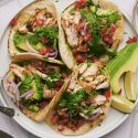 Chicken street tacos with grilled chicken thighs, fresh cilantro, onion, salsa, and lime served on corn tortillas.