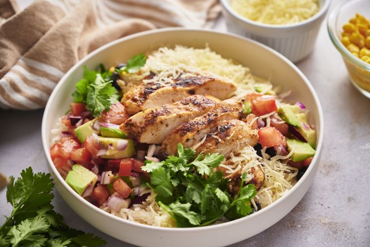 Chicken taco bowls with sliced grilled chicken, pico de gallo, avocado, cilantro, and rice.