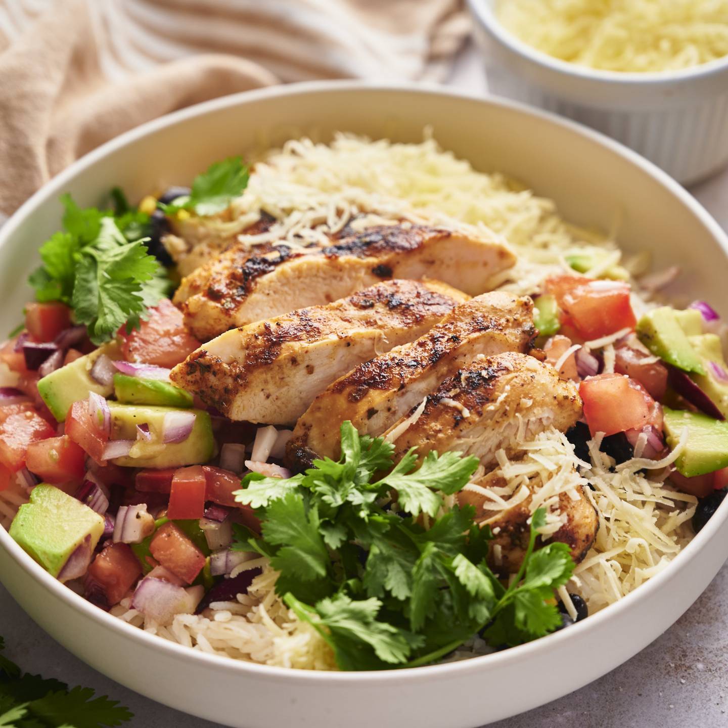 Chicken taco bowls with sliced grilled chicken, pico de gallo, avocado, cilantro, and rice.