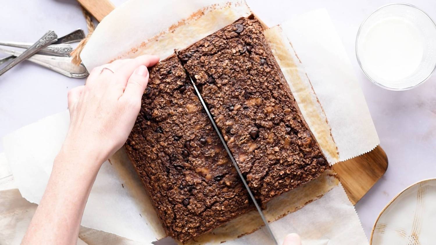 Baked oatmeal with chocolate being cut into squares on a cutting board.