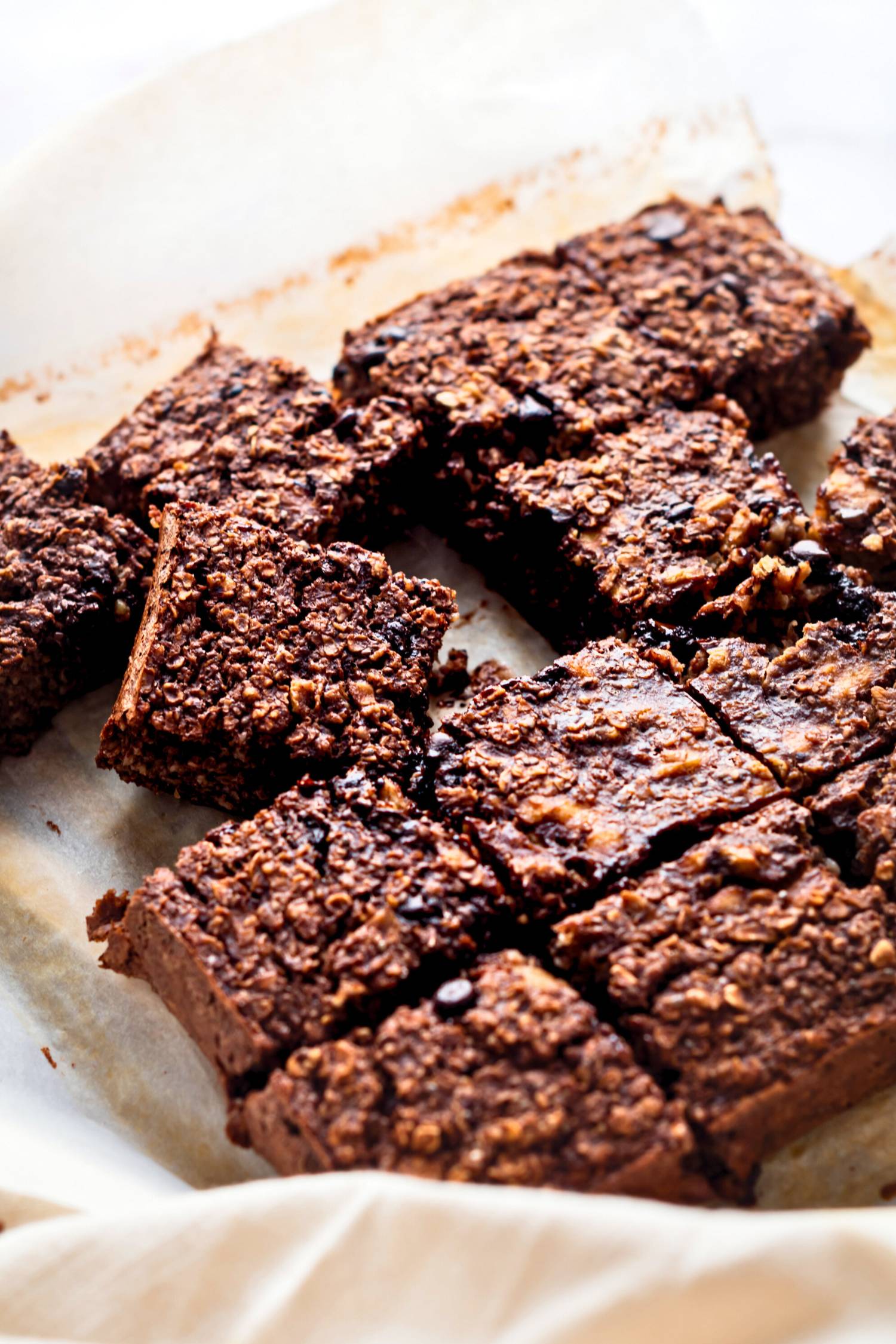 Baked chocolate oatmeal cut into squares on parchment paper. 