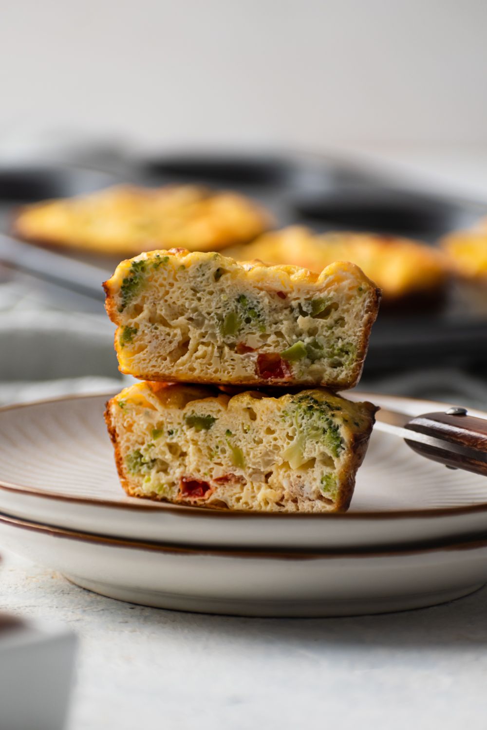 Egg muffins with cottage cheese and vegetables cut in half and stacked on a plate.