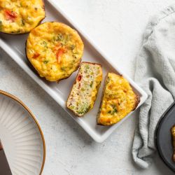 Cottage cheese muffins with mushrooms, tomatoes, and spinach on a wooden board.