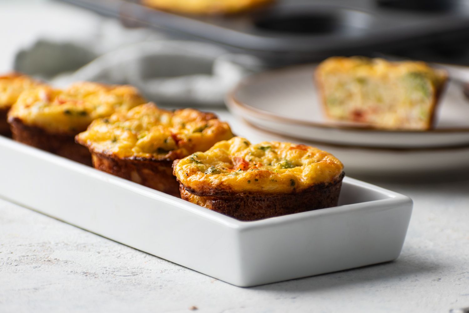 Cottage cheese and egg muffins with vegetables served on a white plate.