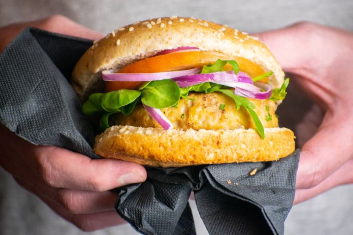 Turkey burgers with lettuce, tomatoes, red onions, cheese, and sprouts on a wheat bun.