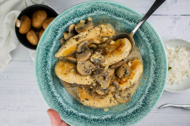 Mushroom chicken with a creamy garlic sauce in a blue bowl.