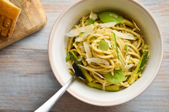 Creamy pesto pasta with zucchini, basil pesto, and Parmesan cheese in a ceramic bowl.