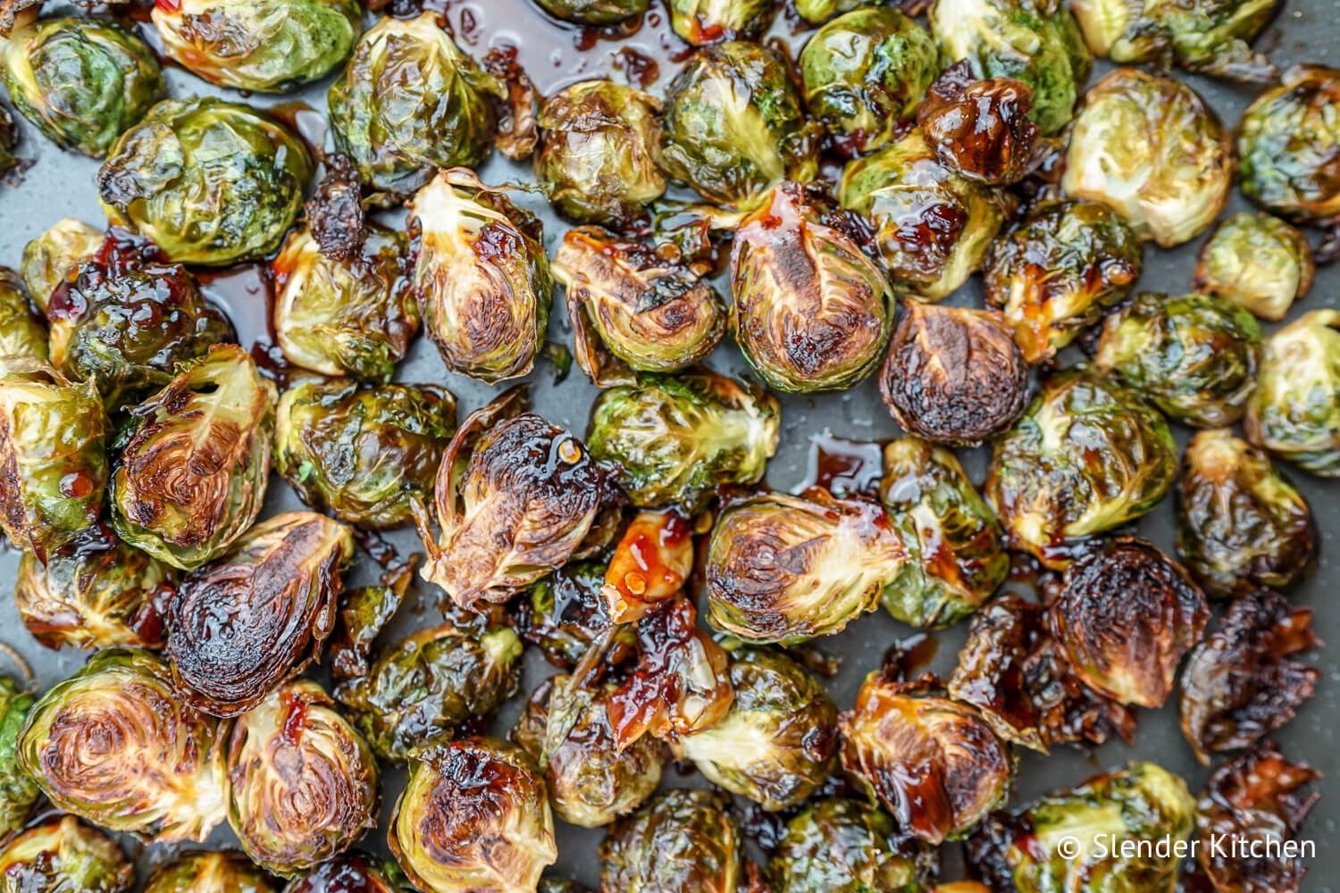 Crispy Asian Brussel sprouts on a baking sheet with soy sauce and honey glaze.