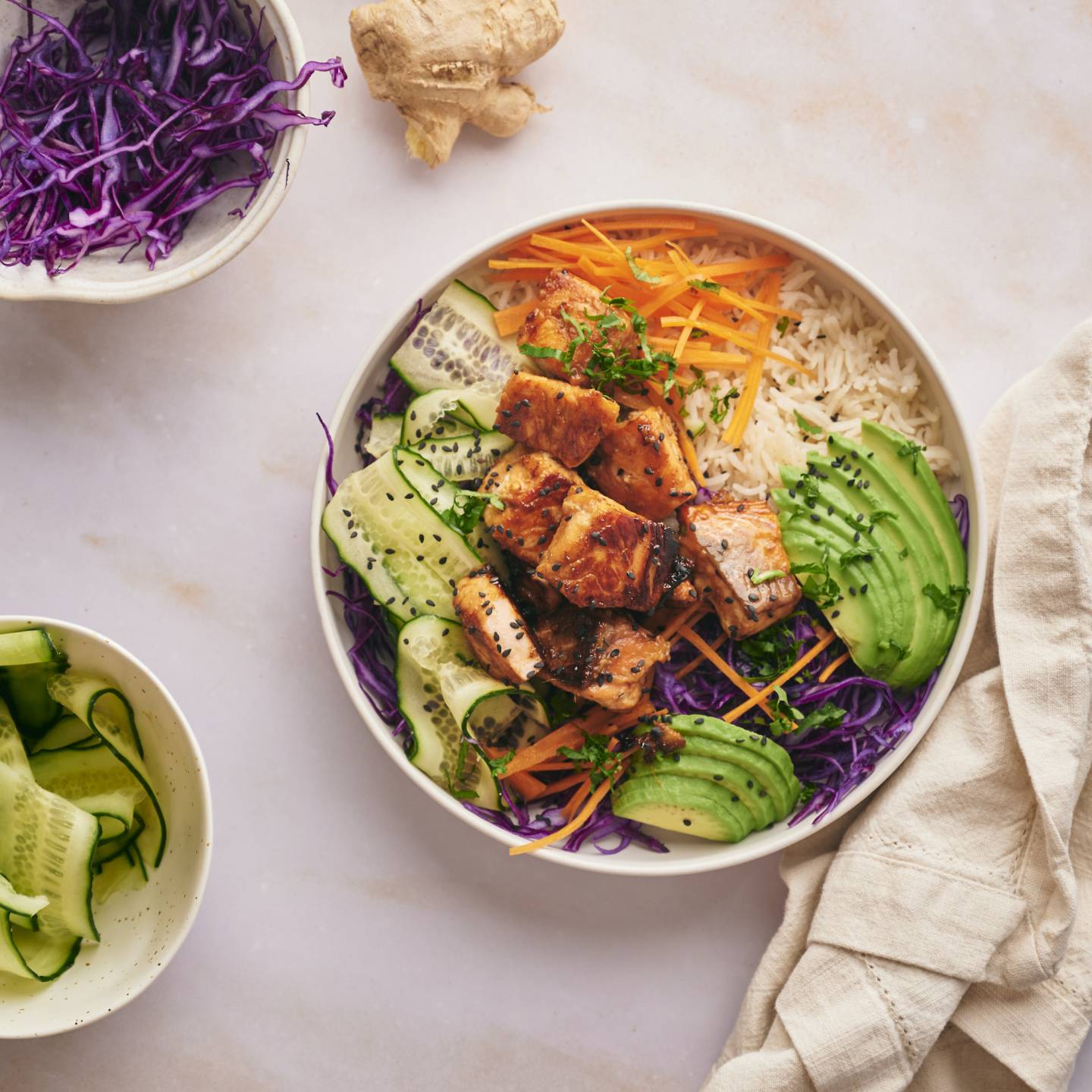 Salmon rice bowls with crispy salmon pieces served with rice, purple cabbage, edamame, carrots, and cucumber.