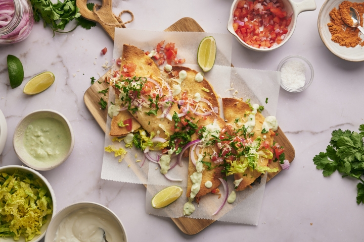 Crispy chicken tacos with corn tortillas stuffed with chicken and beans served with cilantro, salsa, and sour cream.