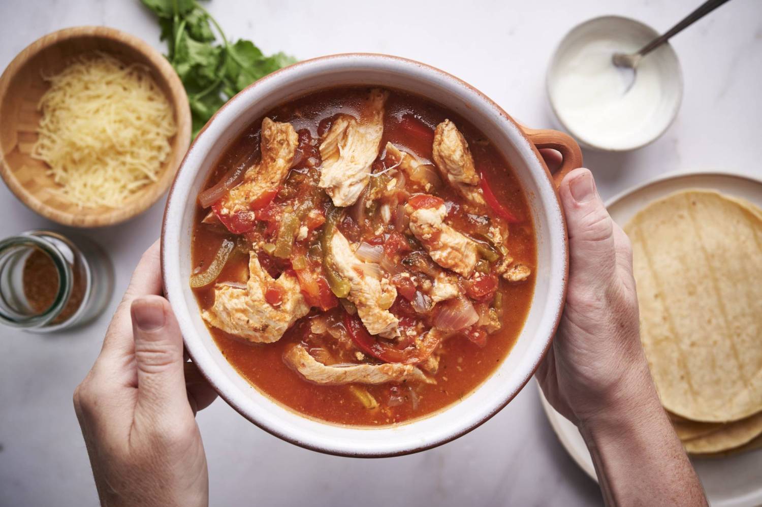 Crockpot chicken fajitas in a bowl with sliced chicken breast, bell peppers, onions, and garlic in tomato broth.