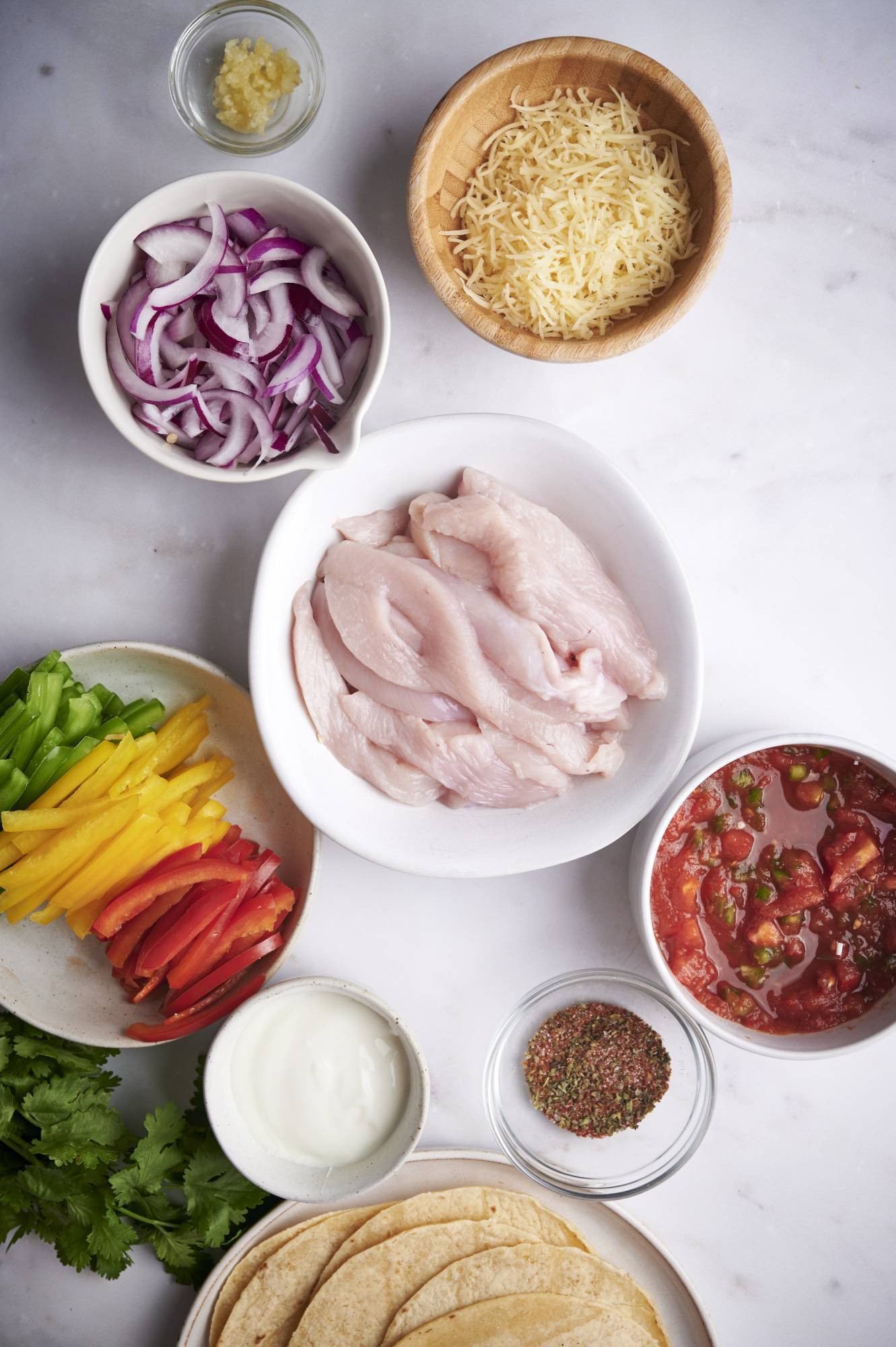 Ingredients for slow cooker chicken fajitas including chicken breast, diced tomatoes, sliced bell peppers, sliced onions, garlic, and fajita seasoning.