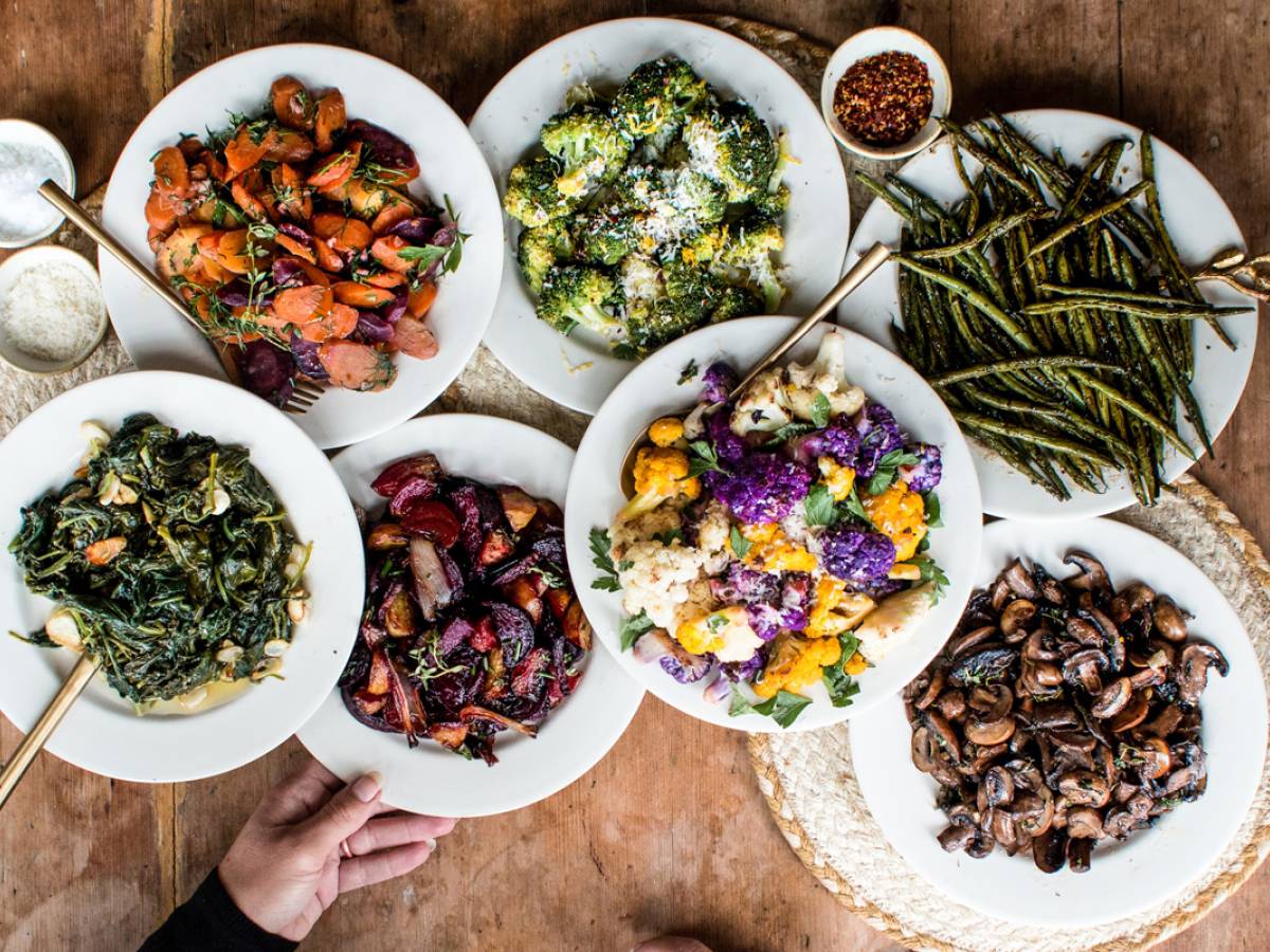 Roasted vegetables including broccoli, cauliflower, mushrooms, beets, and Bok choy on a wooden table.