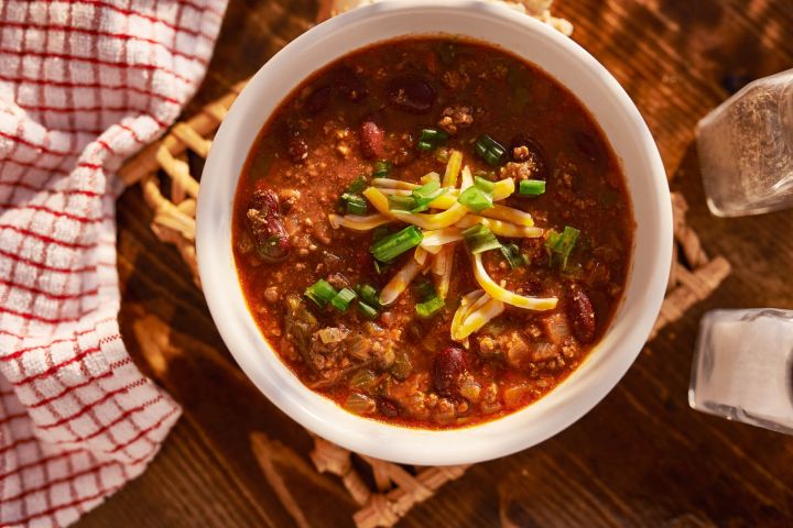 Easy beef chili in a bowl with shredded cheese, green onions, and beans,