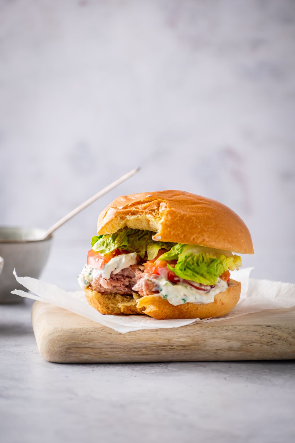 Healthy chicken burgers on a bun with ranch yogurt sauce with a bite taken out.